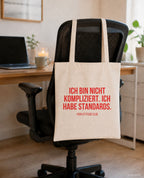 Ich bin nicht kompliziert. Ich habe Standards. – Stoffbeutel mit Spruch beige, am Bürostuhl im Büro