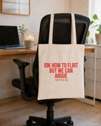 IDK how to flirt but we can argue – Stoffbeutel mit Spruch beige, am Bürostuhl im Büro