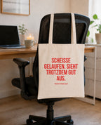 Scheisse gelaufen. Sieht trotzdem gut aus. – Stoffbeutel mit Spruch beige, am Bürostuhl im Büro