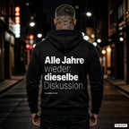 Alle Jahre wieder: dieselbe Diskussion – schwarzer Hoodie mit weißem Backprint, Herren in der Stadt bei Nacht
