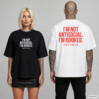 I’M NOT ANTISOCIAL. I’M BOOKED. – Oversize T-Shirt mit Frontprint (Frau, Schwarz) und Backprint (Mann, Weiß)