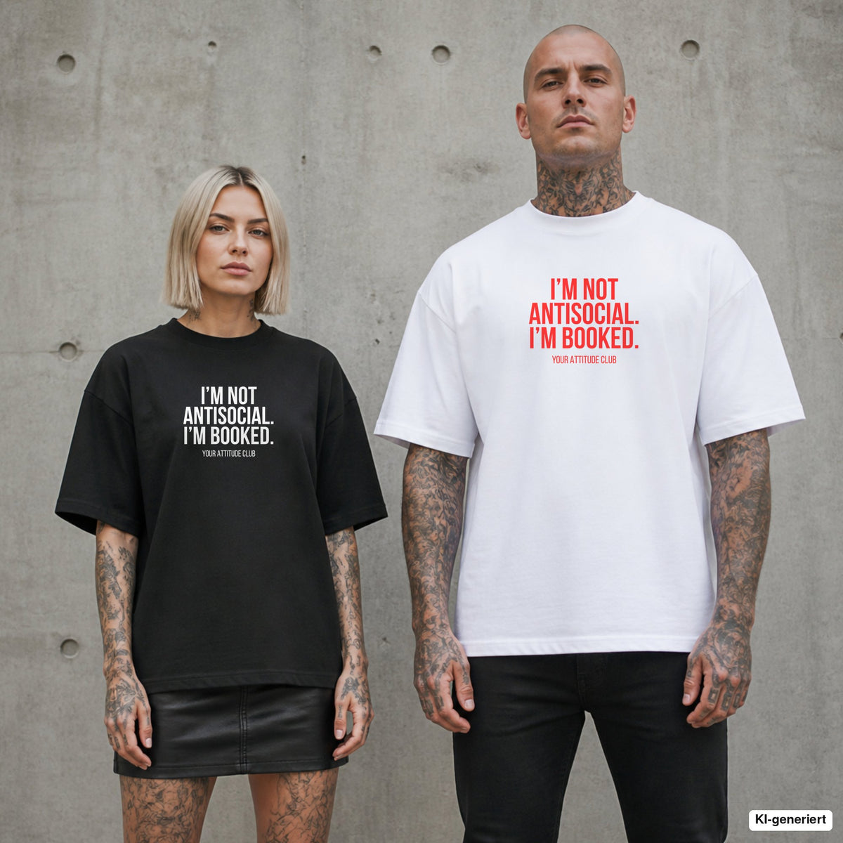 I’M NOT ANTISOCIAL. I’M BOOKED. – Oversize Shirt mit Spruch auf der Brust, Paar in Schwarz und Weiß vor Betonwand