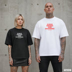 ICH BIN DIE KONSEQUENZ DEINER ENTSCHEIDUNGEN. – Oversize Shirt mit Spruch auf der Brust, Paar in Schwarz und Weiß vor Betonwand