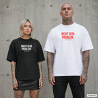 NICHT DEIN PROBLEM. – Oversize Shirt mit Spruch auf der Brust, Paar in Schwarz und Weiß vor Betonwand