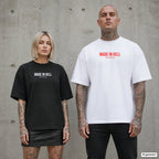MADE IN HELL – Oversize Shirt mit Spruch auf der Brust, Paar in Schwarz und Weiß vor Betonwand