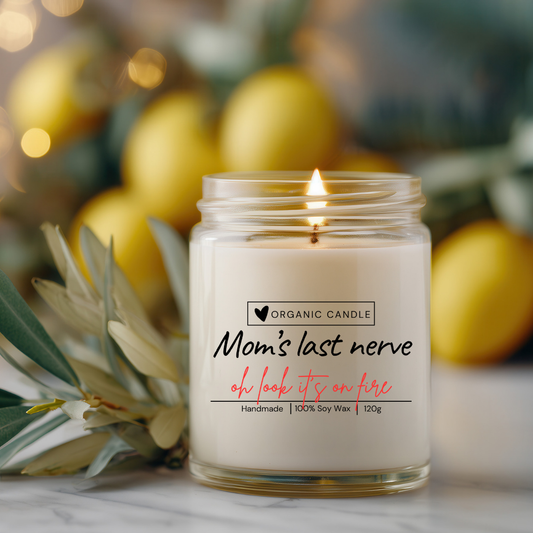 Nahaufnahme einer handgegossenen Sojawachskerze im transparenten Glas mit dem Spruch „Mom’s last nerve. Oh look, it’s on fire“ auf durchsichtigem Etikett