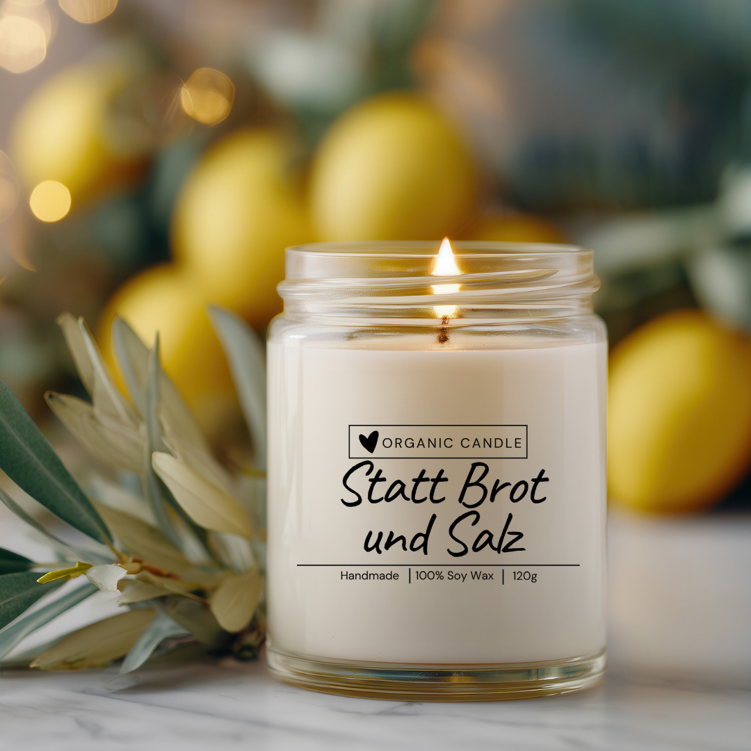 Nahaufnahme einer transparenten Sojawachskerze im Glas mit dem Spruch „Statt Brot und Salz“ auf durchsichtigem Etikett – ideal als Geschenk zum Einzug