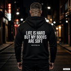 Life is hard but my boobs are soft – schwarzer Hoodie mit weißem Backprint, Herren in der Stadt bei Nacht