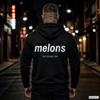 Melons – schwarzer Hoodie mit weißem Backprint, Herren in der Stadt bei Nacht
