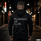 My pronouns are ALL-IN – schwarzer Hoodie mit weißem Backprint, Herren in der Stadt bei Nacht
