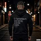 O Tannenbaum, wie nervig sind die Gäste – schwarzer Hoodie mit weißem Backprint, Herren in der Stadt bei Nacht