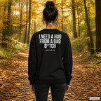 I need a hug from a bad b*tch – schwarzer Pullover mit weißem Backprint, Damen beim Herbstspaziergang