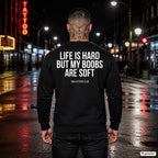 Life is hard but my boobs are soft – schwarzer Pullover mit weißem Backprint, Herren in der Stadt bei Nacht