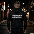 SCHWIERIG? NEIN. ANSPRUCHSVOLL. – schwarzer Hoodie mit weißem Backprint, Herren in der Stadt bei Nacht