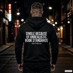 Single because of unrealistic book standards – schwarzer Hoodie mit weißem Backprint, Herren in der Stadt bei Nacht
