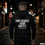 Smut reader. Judge quietly. – schwarzer Hoodie mit weißem Backprint, Herren in der Stadt bei Nacht
