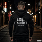 SOZIAL ERSCHÖPFT. – schwarzer Hoodie mit weißem Backprint, Herren in der Stadt bei Nacht