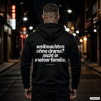 Weihnachten ohne Drama? Nicht in meiner Familie – schwarzer Hoodie mit weißem Backprint, Herren in der Stadt bei Nacht