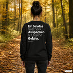 Ich bin das Geschenk. Auspacken auf eigene Gefahr – schwarzer Weihnachtspullover mit weißem Backprint, Damen beim Herbstspaziergang
