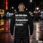 Ich bin das Geschenk. Auspacken auf eigene Gefahr – schwarzer Weihnachtspullover mit weißem Backprint, Herren in der Stadt bei Nacht