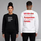 Ich bin das Geschenk. Auspacken auf eigene Gefahr – Weihnachtspullover unisex mit Frontprint (Frau, Schwarz) und Backprint (Mann, Weiß)