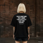I NEED SOMETHING THAT’S MORE THAN COFFEE BUT LESS THAN COCAINE. – schwarzes Oversize T-Shirt mit weißem Backprint, Damen