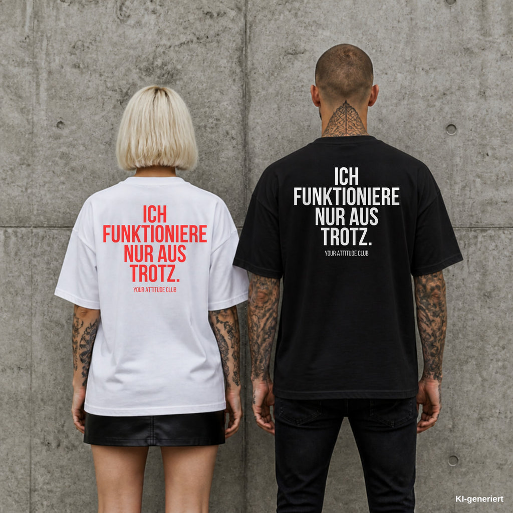 ICH FUNKTIONIERE NUR AUS TROTZ. – Oversize Shirt mit Spruch auf dem Rücken, Paar in Weiß und Schwarz vor Betonwand