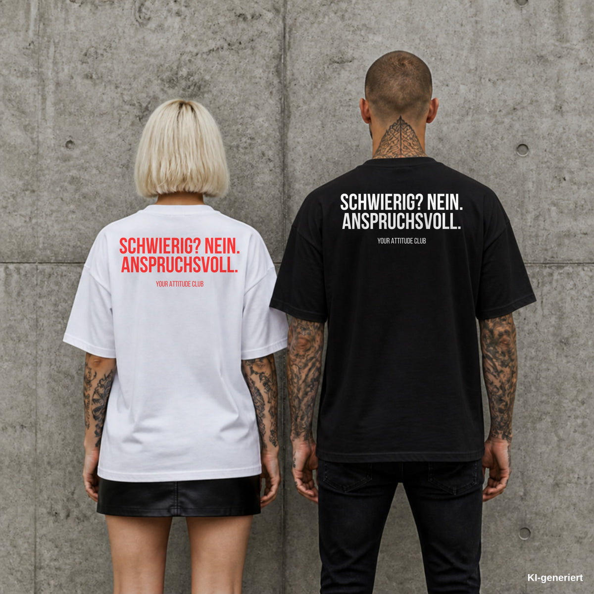 SCHWIERIG? NEIN. ANSPRUCHSVOLL. – Oversize Shirt mit Spruch auf dem Rücken, Paar in Weiß und Schwarz vor Betonwand