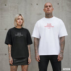 DIE WITH MEMORIES. NOT FUCKING DREAMS – Oversize Shirt mit Spruch auf der Brust, Paar in Schwarz und Weiß vor Betonwand