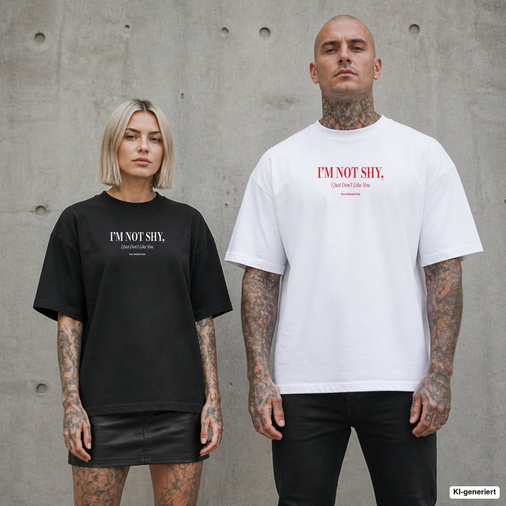 I’M NOT SHY, I JUST DON’T LIKE YOU – Oversize Shirt mit Spruch auf der Brust, Paar in Schwarz und Weiß vor Betonwand
