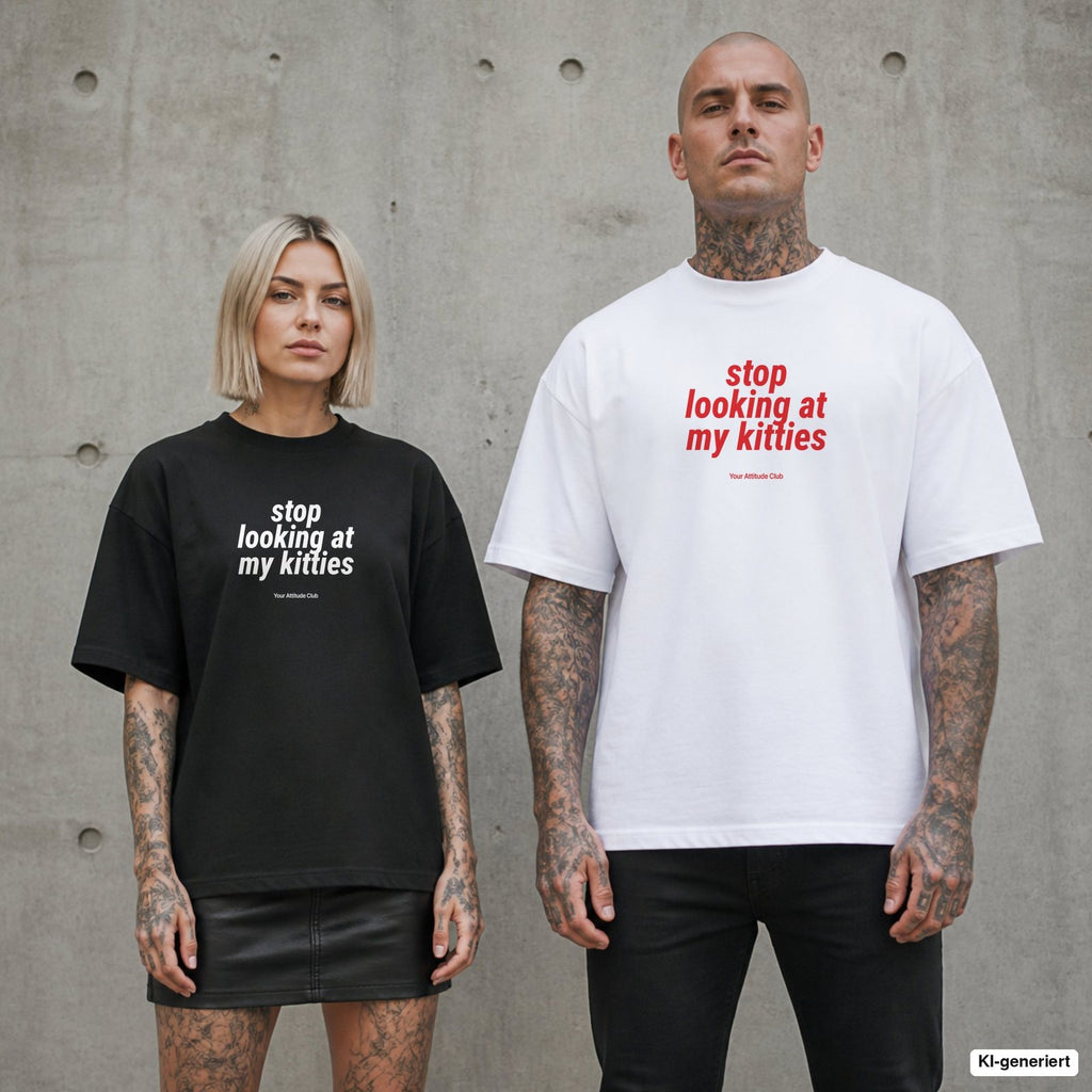STOP LOOKING AT MY KITTIES – Oversize Shirt mit Spruch auf der Brust, Paar in Schwarz und Weiß vor Betonwand