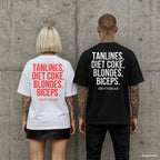 TANLINES, DIET COKE, BLONDES, BICEPS. – Oversize Shirt mit Spruch auf dem Rücken, Paar in Weiß und Schwarz vor Betonwand