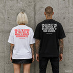 UNLESS I’M SITTING ON YOUR FACE, MY WEIGHT IS NONE OF YOUR BUSINESS. – Oversize Shirt mit Spruch auf dem Rücken, Paar in Weiß und Schwarz vor Betonwand